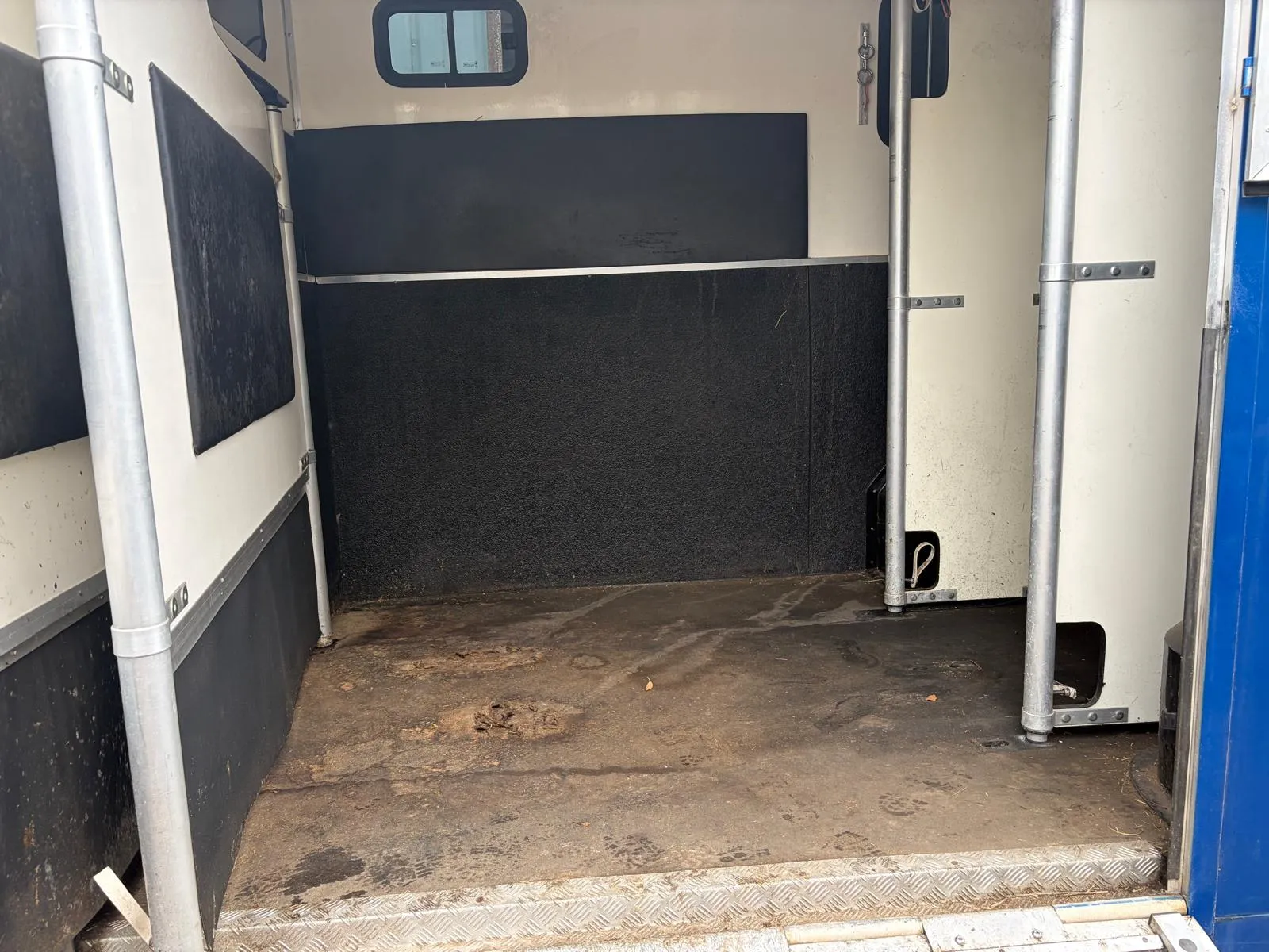The inside of a horse trailer with the door open.